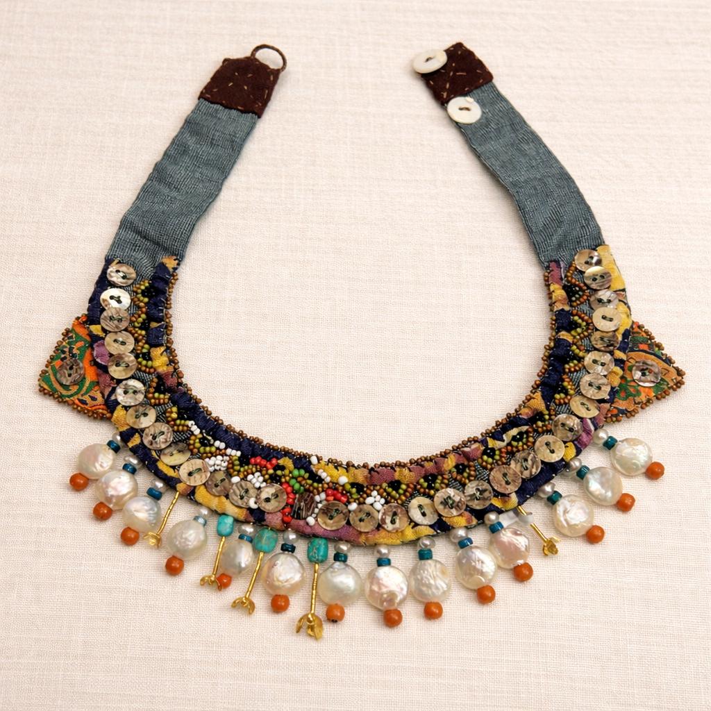 Handcrafted necklace blending vintage textile, coral and turquoise gemstones with mother of pearl.