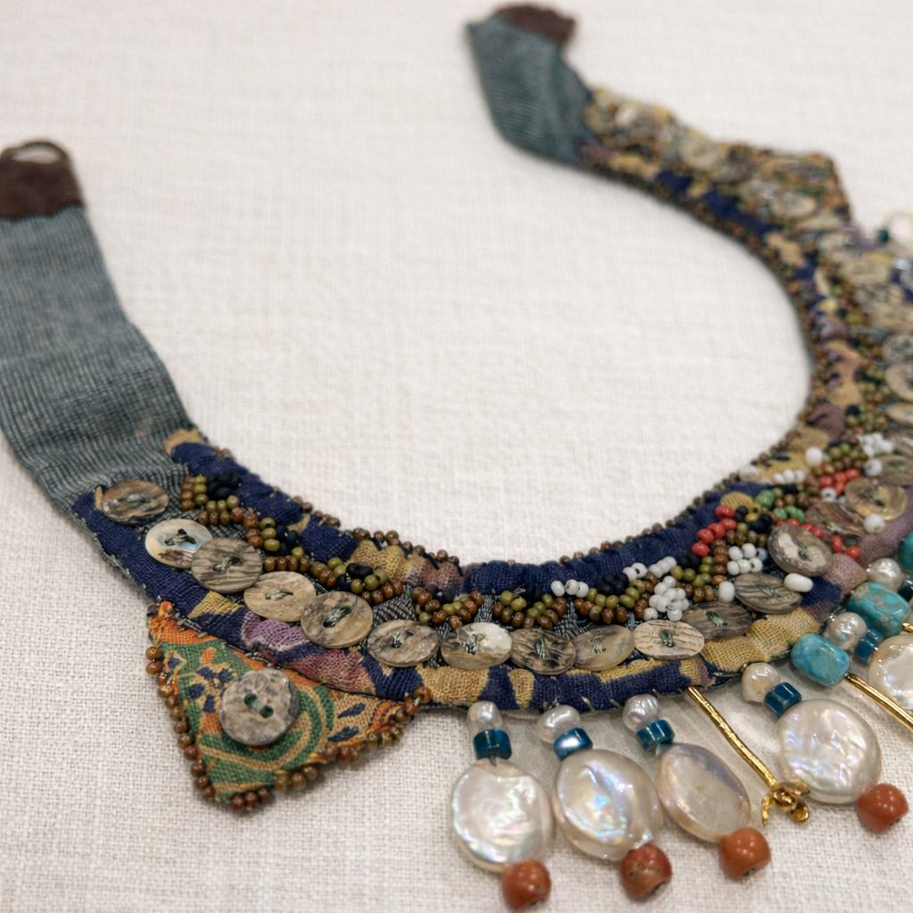 Handcrafted necklace blending vintage textile, coral and turquoise gemstones with mother of pearl.