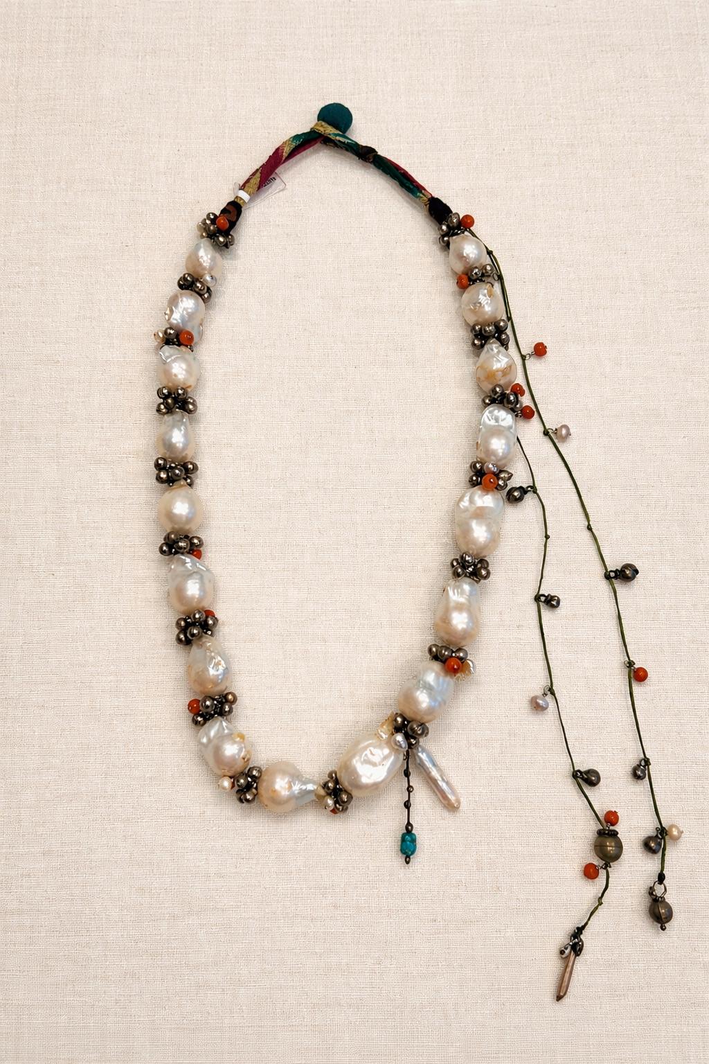 Necklace of calabazo pearls with tiny silver flowers and designs on the left
